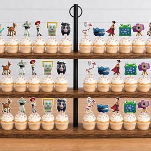 May include: A three-tiered wooden cupcake stand holding rows of cupcakes topped with various character-themed paper toppers, including figures like a white spork, a brown horse, a green space ranger, a cowgirl, a black pig, and a purple camera.