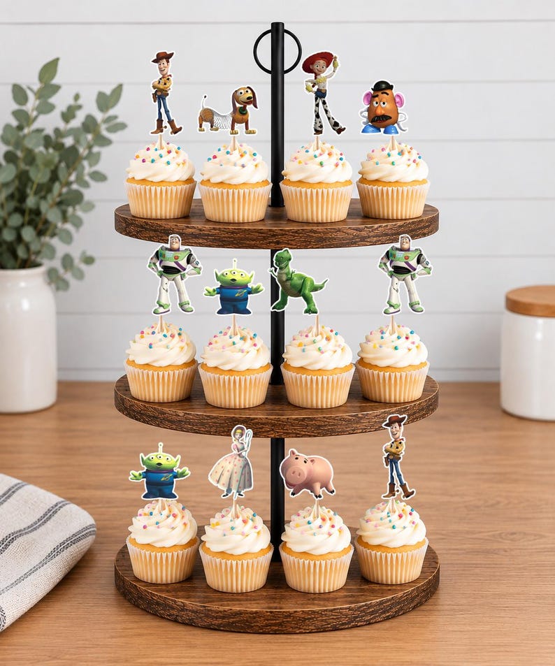 May include: A three-tiered wooden cupcake stand holding twelve cupcakes topped with white frosting, colourful sprinkles, and various character-themed paper toppers including a cowboy, a space ranger, a green alien, a dinosaur, and a pig.