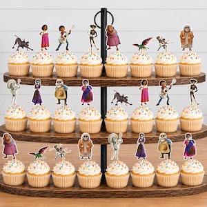 May include: A three-tiered wooden cupcake stand holding twenty-two cupcakes, each topped with a colourful paper cutout character from the movie Coco. The cupcakes feature white frosting with multicoloured sprinkles and are arranged on dark wood trays.