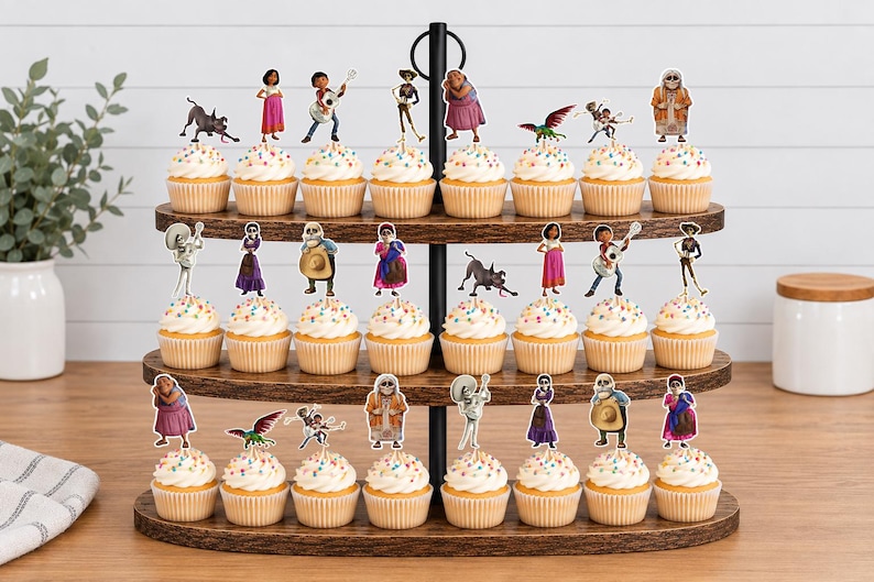 May include: A three-tiered wooden cupcake stand holding twenty-two cupcakes, each topped with a colourful paper cutout character from the movie Coco. The cupcakes feature white frosting with multicoloured sprinkles and are arranged on dark wood trays.