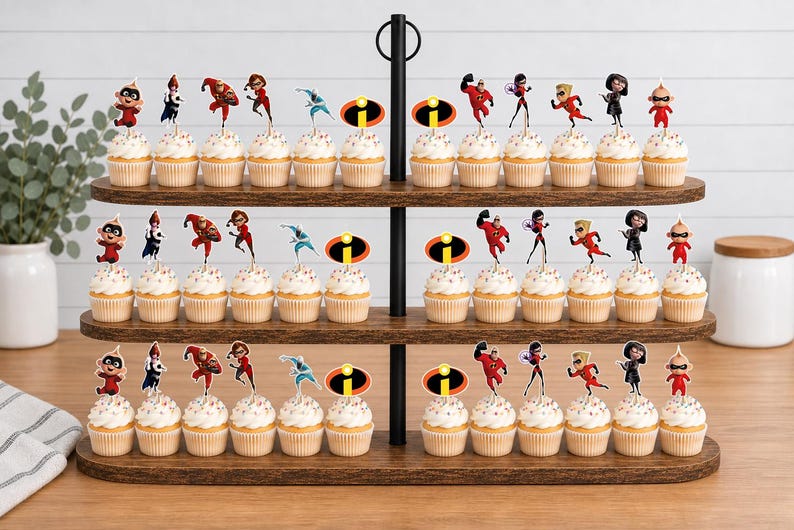 Op de afbeelding: Een houten cupcake-standaard met drie niveaus vol cupcakes, versierd met papieren prikkers van personages uit The Incredibles, waaronder Mr. Incredible, Elastigirl, Violet, Dash, Jack-Jack en het iconische oranje met zwarte logo.