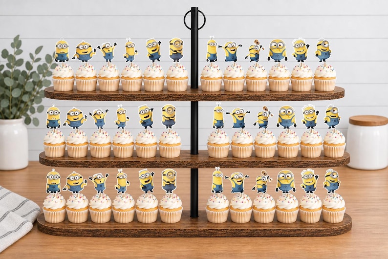 May include: A three-tiered wooden cupcake stand holding numerous cupcakes topped with yellow Minion character paper toppers. Each cupcake features a light-colored frosting with colorful sprinkles, arranged neatly across the three oval wooden shelves.