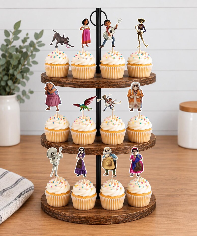 May include: A three-tiered wooden cupcake stand holding twelve cupcakes topped with white frosting and colourful sprinkles. Each cupcake features a paper cutout topper depicting various characters and creatures from the movie Coco.