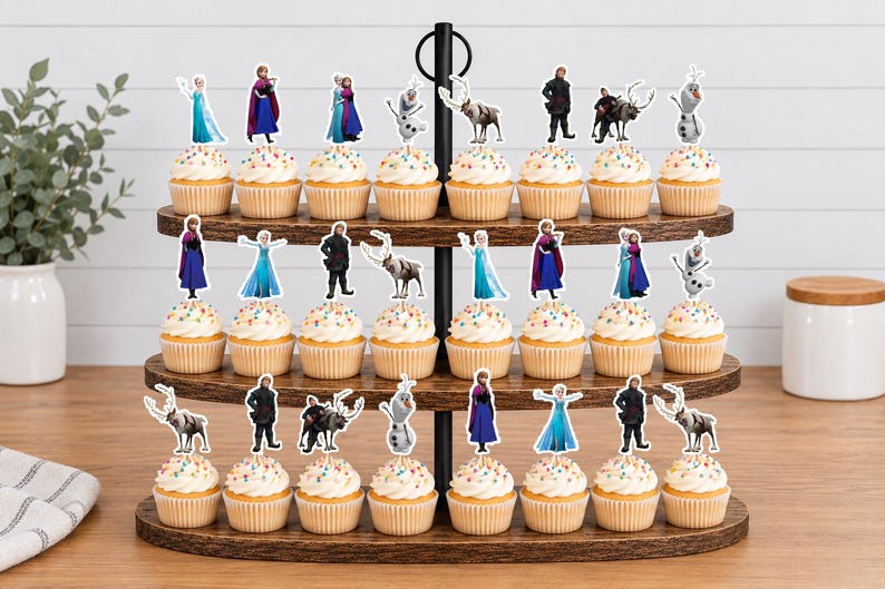 以下が含まれることがあります： 3段の木製カップケーキスタンドに24個のカップケーキが並んでおり、それぞれに映画「アナと雪の女王」のキャラクターであるエルサ、アナ、クリストフ、スヴェン、オラフの紙製切り抜きが飾られており、カラフルな衣装と華やかなデザインが特徴です。