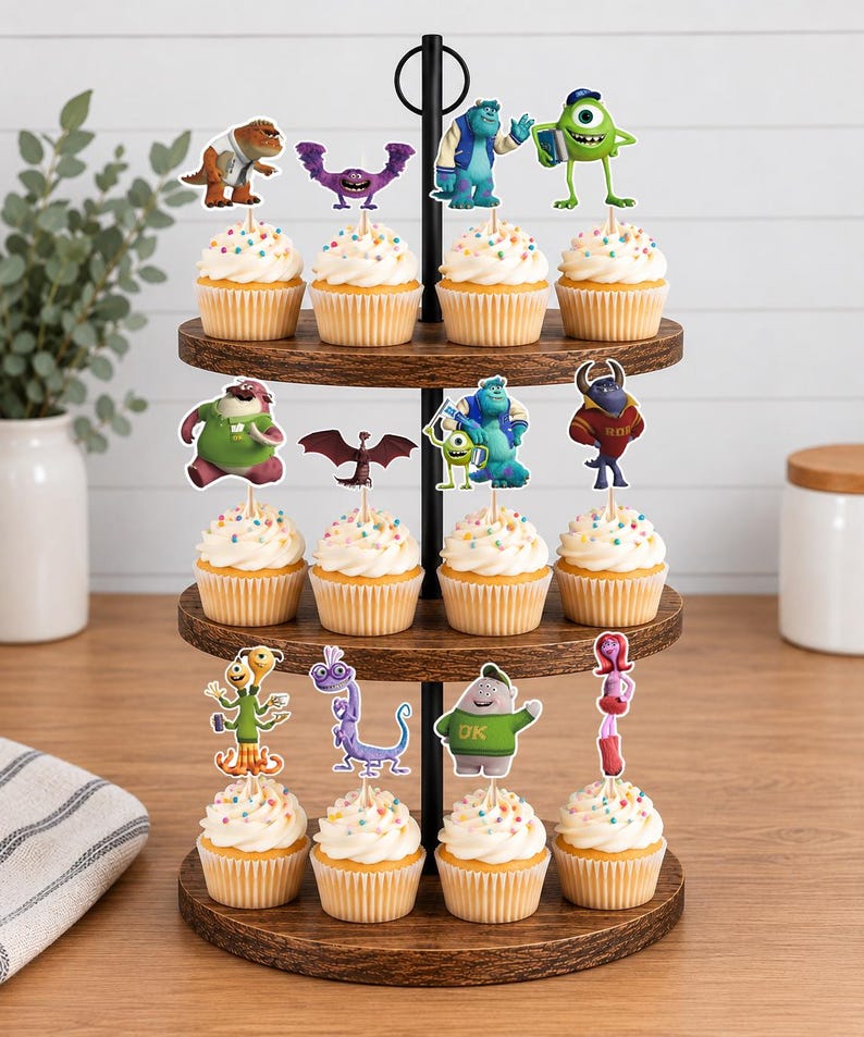 May include: A three-tiered wooden cupcake stand holding twelve cupcakes, each topped with a paper cutout of a character from the Monsters University film. The cupcakes feature white frosting with colorful sprinkles and are arranged on circular trays.