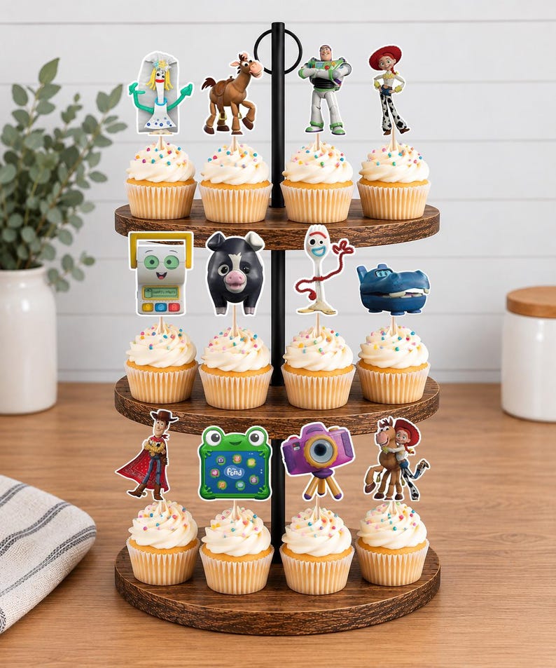 May include: A three-tiered wooden cupcake stand holding twelve cupcakes topped with colorful sprinkles and various character-themed paper toppers, including figures like a space ranger, a cowgirl, a spork, a horse, and a purple camera.