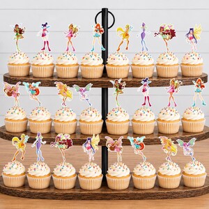 May include: A three-tiered wooden cupcake stand holding twenty-four cupcakes, each topped with a colorful paper cutout of a fairy character. The stand features a black metal central pole and handle, displaying a variety of animated character designs.