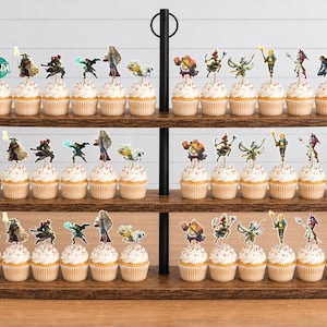 May include: A three-tiered wooden cupcake stand holding numerous cupcakes topped with various Legend of Zelda character paper toppers. Each topper features a unique character illustration or the circular teal Zelda logo with white text.