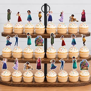 Pode incluir: Um suporte de madeira para cupcakes de tr&ecirc;s n&iacute;veis com vinte e quatro cupcakes, cada um decorado com um recorte de papel apresentando personagens e uma casa do filme Encanto. O suporte possui uma al&ccedil;a central de metal preto.