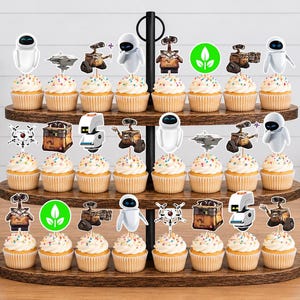 May include: A three-tiered wooden cupcake stand holding twenty-four cupcakes, each topped with a paper cutout featuring characters and symbols from the movie Wall-E, including Wall-E, Eve, and green plant icons, arranged on a wooden surface.