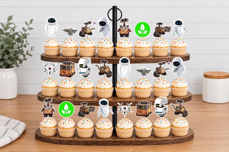 May include: A three-tiered wooden cupcake stand holding twenty-four cupcakes, each topped with a paper cutout featuring characters and symbols from the movie Wall-E, including Wall-E, Eve, and green plant icons, arranged on a wooden surface.