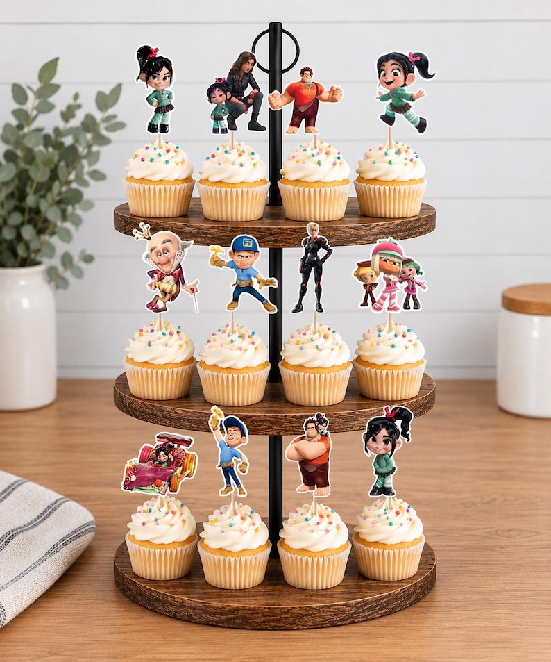 May include: A three-tiered wooden cupcake stand holding twelve cupcakes topped with white frosting and colorful sprinkles. Each cupcake features a Wreck-It Ralph character cutout topper, including Ralph, Vanellope, Felix, and other movie figures.