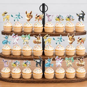 May include: A three-tiered wooden stand holding twenty-four cupcakes, each topped with a colorful paper cutout of various Eevee evolution characters. The cupcakes feature white frosting with multi-colored sprinkles, arranged in rows on the dark wood.
