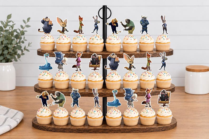 Pu&ograve; includere: Un'alzata per cupcake in legno a tre livelli contenente ventiquattro cupcake, ognuno sormontato da una sagoma di carta colorata di un personaggio di Zootopia. I cupcake hanno una glassa bianca con zuccherini multicolori sui ripiani in legno.