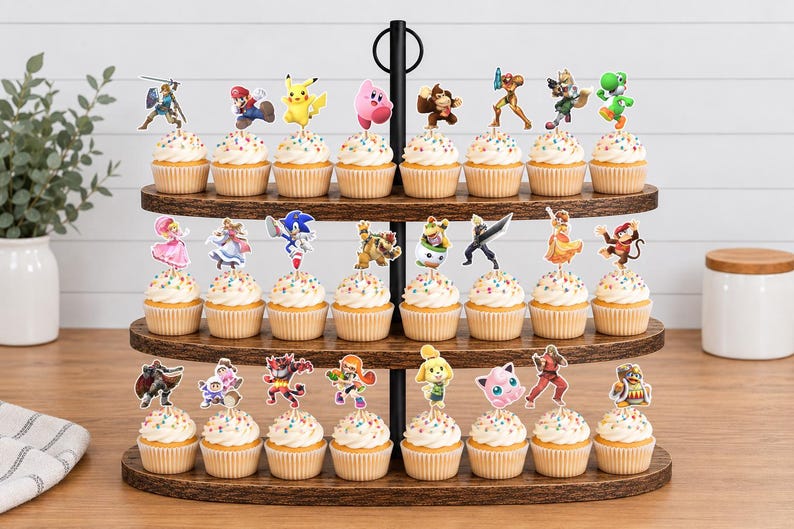 May include: A three-tiered wooden cupcake stand holding twenty-four cupcakes, each topped with a colorful paper cutout of a video game character. The stand features a central black metal rod and oval-shaped shelves with a dark brown wood grain finish.