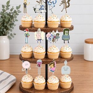K&ouml;nnte beinhalten: Ein dreist&ouml;ckiger Cupcake-St&auml;nder aus Holz mit zw&ouml;lf Cupcakes, die mit bunten Streuseln und Papieraufstellern verschiedener Zeichentrickfiguren aus der Serie Regular Show wie Mordecai, Rigby, Benson, Skips, Muscle Man und Pops verziert sind.