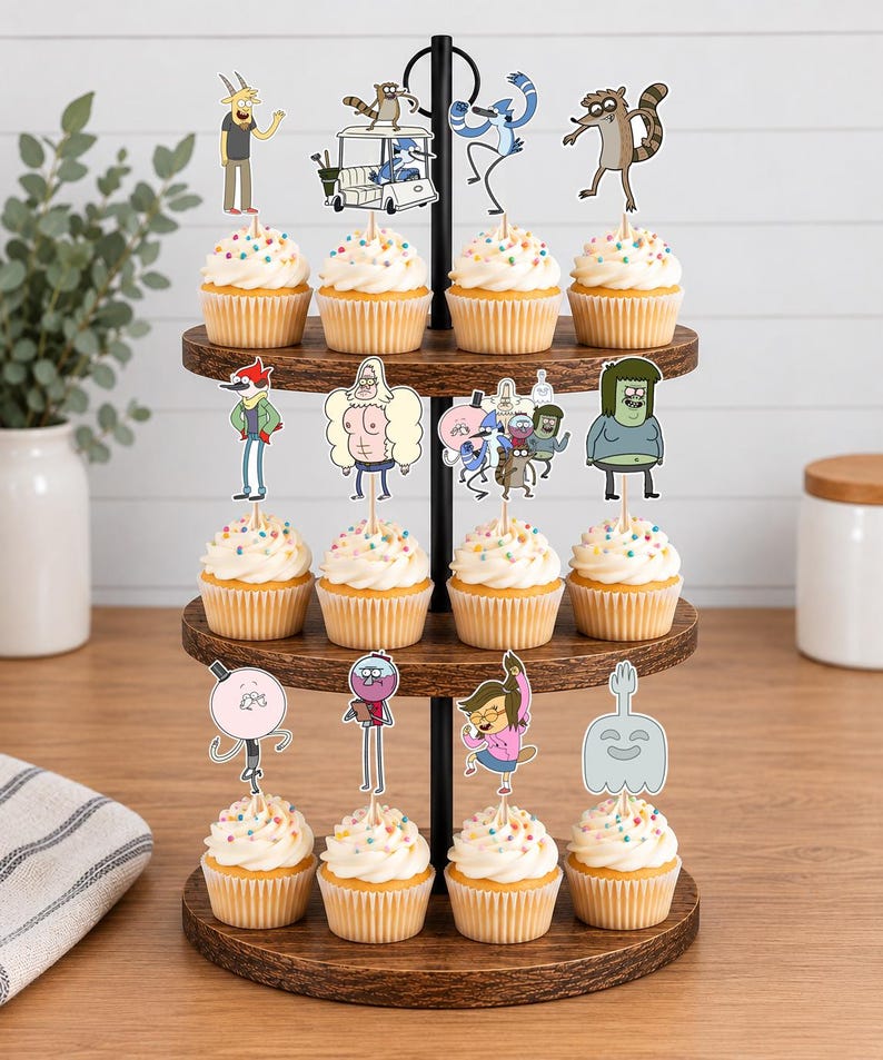 K&ouml;nnte beinhalten: Ein dreist&ouml;ckiger Cupcake-St&auml;nder aus Holz mit zw&ouml;lf Cupcakes, die mit bunten Streuseln und Papieraufstellern verschiedener Zeichentrickfiguren aus der Serie Regular Show wie Mordecai, Rigby, Benson, Skips, Muscle Man und Pops verziert sind.