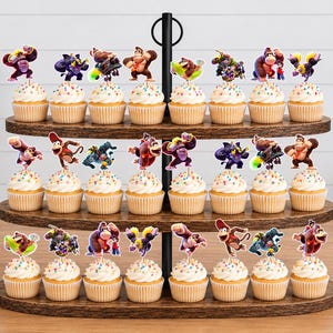 May include: A three-tiered wooden cupcake stand holding twenty-two cupcakes, each topped with a colorful paper cutout of Donkey Kong characters. The stand features a central black metal rod with a ring handle at the top, displaying various poses.