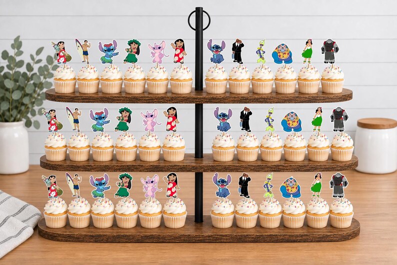 May include: A three-tiered wooden cupcake stand holding rows of cupcakes topped with colorful paper character cutouts. The decorations feature various animated figures including blue and pink creatures, a surfer, and a person in a red dress.
