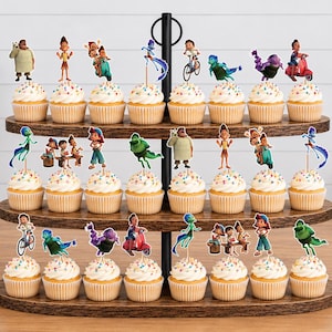 Puede incluir: Un soporte de madera para cupcakes de tres niveles con veinticuatro cupcakes, cada uno decorado con un peque&ntilde;o recorte de papel de personajes de la pel&iacute;cula Luca. Los cupcakes muestran varias escenas con los personajes en acci&oacute;n.