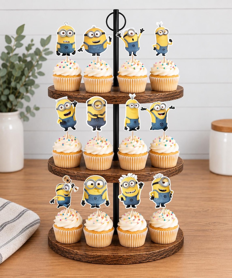 May include: A three-tiered wooden cupcake stand holding twelve cupcakes, each topped with a white frosting swirl, colorful sprinkles, and a decorative paper cutout of a yellow Minion character wearing blue overalls in various poses.