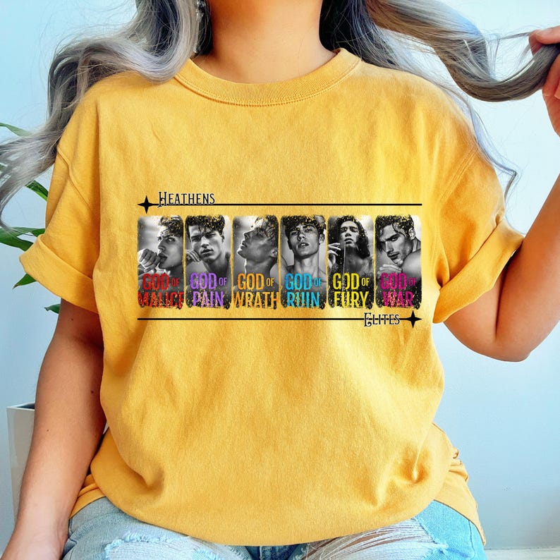 K&ouml;nnte beinhalten: Ein gelbes T-Shirt mit einem schwarz-wei&szlig;en Grafikdruck von sechs M&auml;nnergesichtern. Der Text "HEATHENS" und "ELITES" ist auf dem Shirt gedruckt. Der Text "GOD OF" ist &uuml;ber jedem Gesicht gedruckt, mit einem anderen farbigen Wort unter jedem Gesicht: "MALICE", "PAIN", "WRATH", "RUIN", "FURY", "WAR".