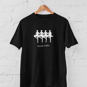 Könnte beinhalten: Schwarzes T-Shirt mit einer weißen Silhouette von vier Ballerinas in einer Reihe, mit dem Text "Swan Lake" darunter.