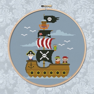 Könnte beinhalten: Ein Kreuzstichmuster eines Piratenschiffs mit einer Totenkopf- und Knochenflagge, einem Papagei und drei Piraten. Das Schiff ist braun mit einem rot-weiß gestreiften Segel. Der Hintergrund ist blau mit weißen Wolken.