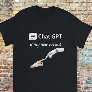 Puede incluir: Camiseta negra con texto blanco que dice "Chat GPT is my new Friend". El texto está acompañado por un gráfico de una mano humana y una mano robótica tocándose las yemas de los dedos.