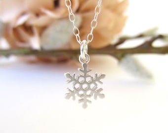 May include: A silver snowflake pendant necklace. The snowflake is delicate and intricate, with a simple chain.