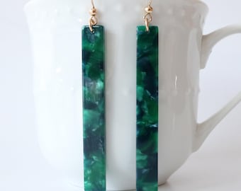May include: A pair of long, green and blue marbled rectangle earrings with gold hooks.