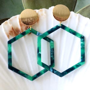 May include: A pair of green and blue geometric hexagon earrings with gold tops.