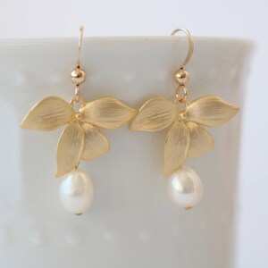 May include: Gold flower earrings with a single pearl dangling from each earring.