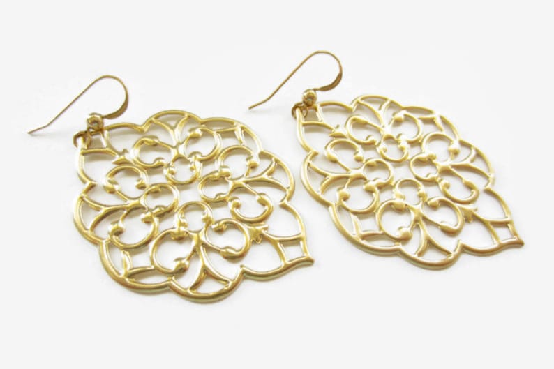Puede incluir: Un par de pendientes de filigrana dorada con un dise&ntilde;o delicado e intrincado. Los pendientes tienen forma de l&aacute;grima y un patr&oacute;n floral.