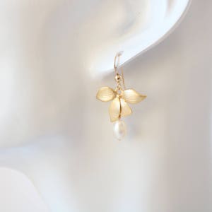 May include: Gold flower earrings with a single pearl dangling from the bottom.