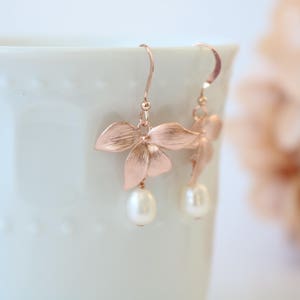 May include: Rose gold earrings with a delicate flower design and a pearl drop.