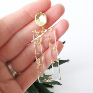 May include: Clear rectangular earrings with gold flecks and a gold top.