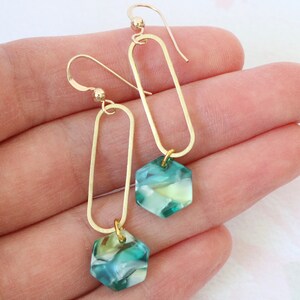 May include: Gold earrings with a teardrop-shaped design and a hexagonal green and white stone pendant.