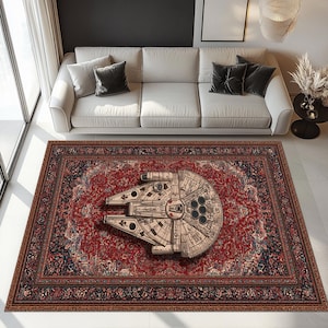 Peut inclure: Un grand tapis rectangulaire avec un motif floral rouge et marine. Le tapis présente une image détaillée du vaisseau spatial Millennium Falcon au centre. Le tapis est placé dans un salon.