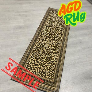 a leopard print rug on a wooden floor, with a red stamp that reads "SAMPLE" and a green and yellow text overlay that says "AGD RUG".