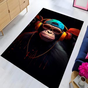 Può includere: Un tappeto nero e rosso con un'immagine di un cartone animato di una scimmia che indossa occhiali da sole, un berretto da baseball blu e cuffie. La scimmia indossa una catena d'oro intorno al collo.