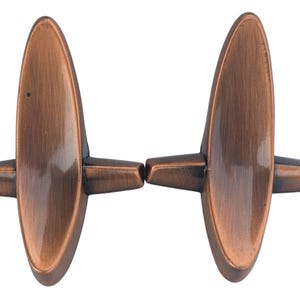 May include: Two copper-colored cufflinks with an oval center and two rectangular wings on each side. The cufflinks have a metallic finish and a symmetrical design, suitable for formal wear.