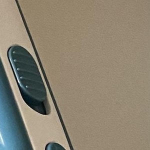 May include: A white and teal handheld vacuum cleaner with a clear dustbin. The vacuum is mounted on a white wall-mounted charging station.