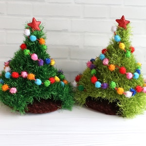 Peut inclure: Deux décorations de sapin de Noël faites à la main. Les arbres sont verts avec une base marron, décorés de pompons colorés et surmontés d'une étoile rouge. Les arbres mesurent environ 15 cm de haut.