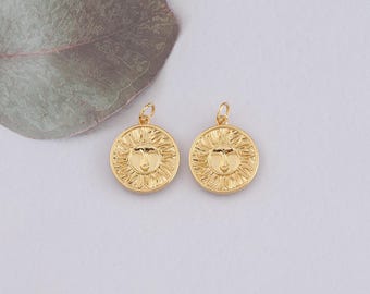 May include: Two gold-toned sun pendant charms with a face design. The charms are round and have a textured surface.
