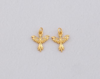 May include: Two gold-colored bird charms with small, clear gemstones. The charms have a loop at the top for hanging and are set against a white background. The bird design features outstretched wings and a detailed tail.