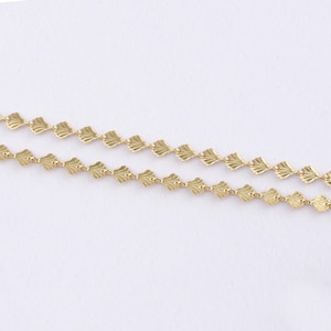 May include: Two strands of delicate gold-colored chain. Each chain features a repeating pattern of small, fan-shaped charms. The chains are displayed against a plain white background, highlighting the intricate design and color.