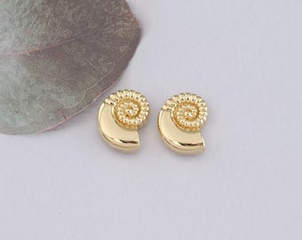 May include: A pair of gold-toned earrings shaped like seashells. The earrings have a detailed spiral design.