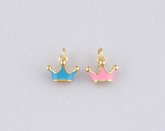 May include: Two small crown charms. One is light blue, the other is pink. Both have gold-colored metal details and a loop at the top for hanging. The crowns have a classic, regal design.
