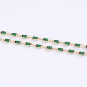 May include: Two delicate gold necklaces with emerald green rectangular stones. The stones are evenly spaced and set in gold bezels. The necklaces are displayed against a white background.